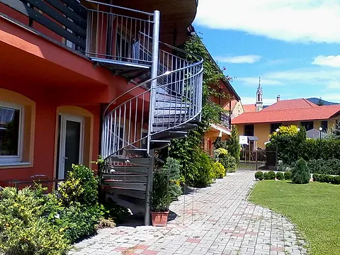 Točité kovové schodisko pri penzióne a dláždený chodník popri trávniku