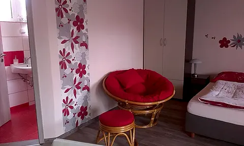 Červené ratanové kreslo a pohľad do kúpeľne v izbe č. 11