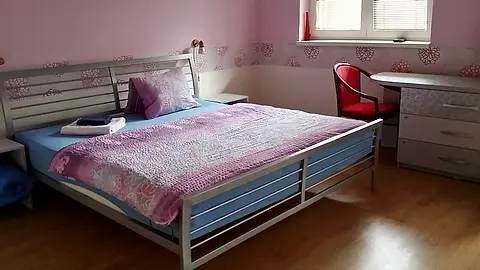 Izba č. 5 s manželskou posteľou, písacím stolom a ružovými stenami