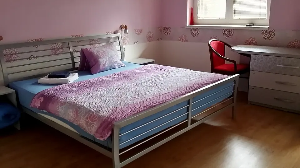 Izba č. 5 s manželskou posteľou, písacím stolom a ružovými stenami