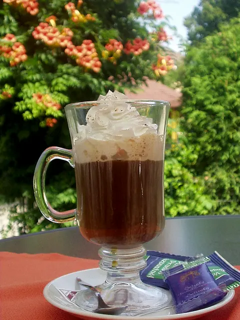 Viedenská káva so šľahačkou na stolíku v kvitnúcej záhrade