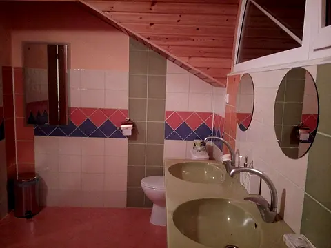 Podkrovná kúpeľňa izby č. 12 s okrúhlymi zrkadlami a toaletou