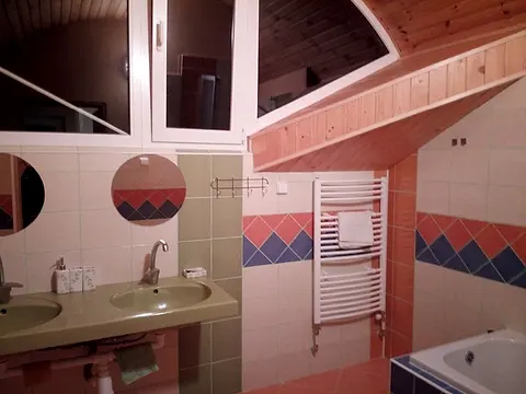 Kúpeľňa izby č. 12 s dvoma umývadlami a sedacou vaňou pod šikmým stropom